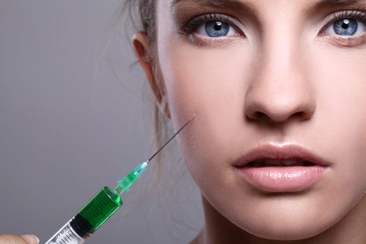 Close up of beautiful woman gets an injection in her face