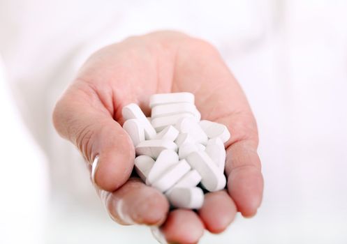 Close up of doc hand holding pills isolated on a white