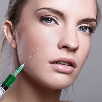 Close up of beautiful woman gets an injection in her face