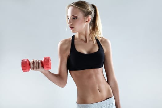 Slim and sporty girl do exercise with red dumbbells