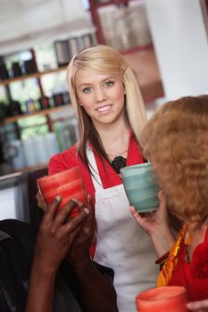 Smiling teenage waitress hands mugs to customers in restaurant