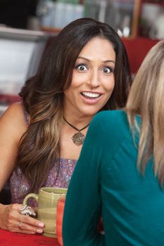 Astonished mature woman talking with friend in coffeehouse