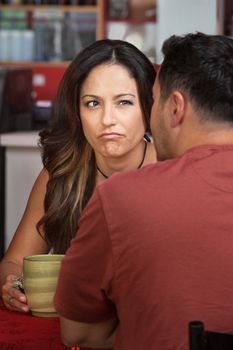 Doubtful woman looking at man sitting in cafe