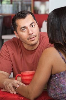 Hispanic man comforting female and holding her hand in cafe