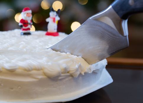 Slice out of iced christmas cake with lights of xmas tree out of focus in background