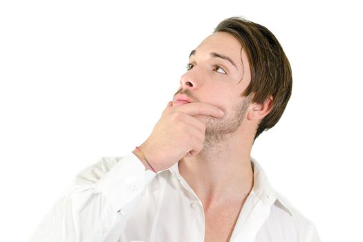 Attractive young man holding his chin, looking up and thinking