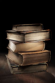 Dark and moody still life with worn and tattered old books.