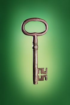 Old big antique key on green background.