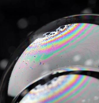 Closeup of soap bubbles. The iridescent colours of soap bubbles are caused by interfering of (internally and externally) reflected light waves and are determined by the thickness of the film. 