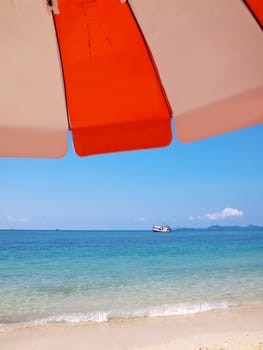 Sunshade on beach with boat in island in sunny summer day