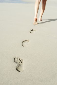 A young woman walking on the sand.