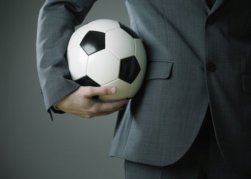 Elegant businessman holding a soccer ball, close up