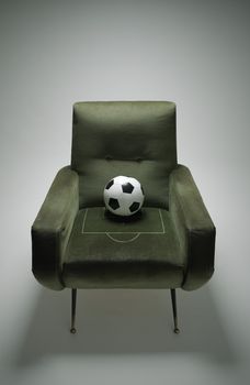 Soccer ball on a green chair, conceptual photo