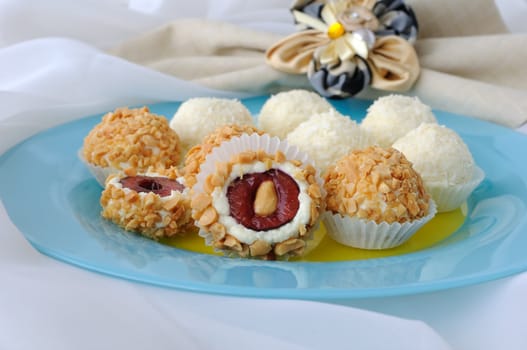 Cheese balls stuffed with cherries in peanuts and coconut flakes