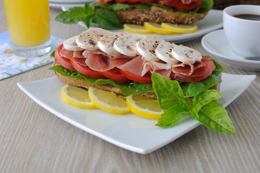 Sandwich with ham and mushrooms with a cup of coffee and juice