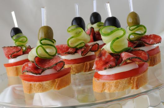 Canape of the baguette with salami on a glass base