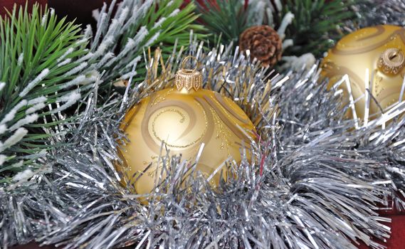 Christmas balls against the backdrop of tinsel with pine branches and cones