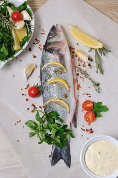 of fresh sea bass with lemon and spices and herbs on paper