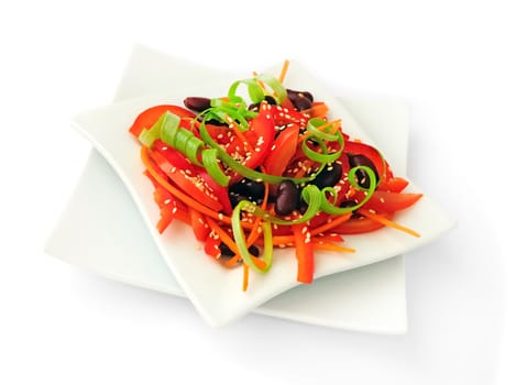 A salad of tomatoes, sweet peppers, red beans, carrots with sesame