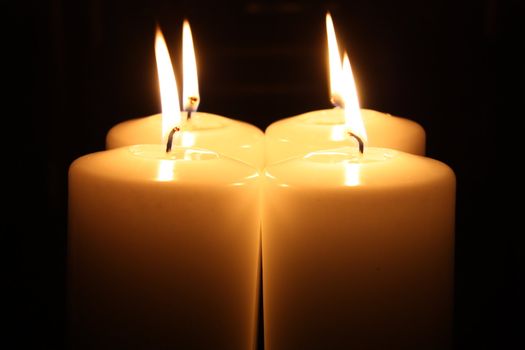 Four big candles alight in a darkness