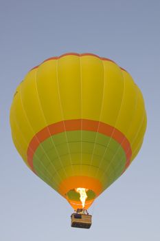 Hot air balloon with burner lit rises in a clear blue sky. Pushkar Fair, Rajasthan, India