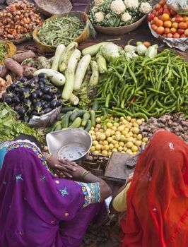 Indian ladies in brightly colored saris selling fruit and vegetables at a street market in Pushkar, Rajasthan, India