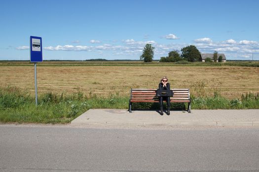 lonely woman waiting for a bus in rural area