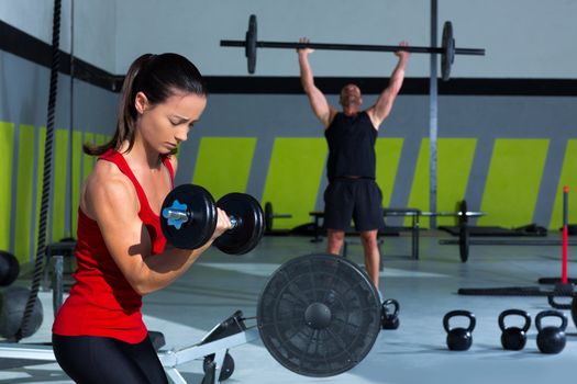girl dumbbell and man weight lifting bar workout at crossfit gym