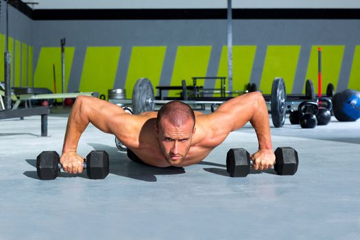 Gym man push-up strength pushup exercise with dumbbell in a crossfit workout