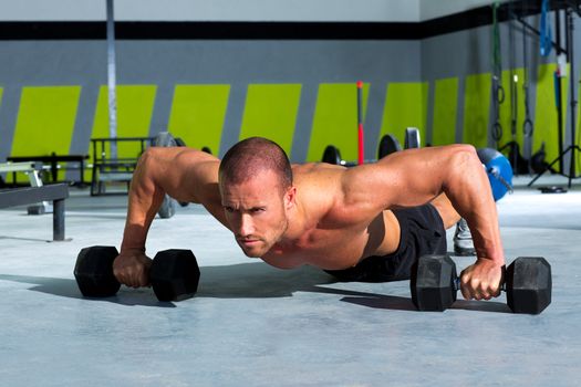 Gym man push-up strength pushup exercise with dumbbell in a crossfit workout