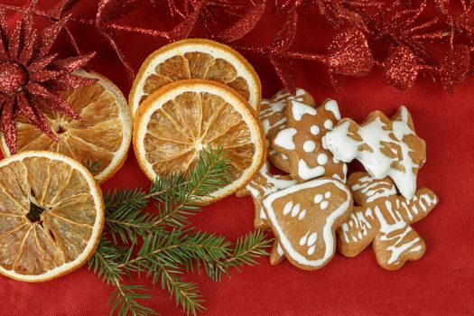 christmas background with needles. orange slices and gingerbreads on red