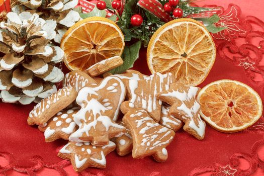christmas background with needles. orange slices and gingerbreads on red