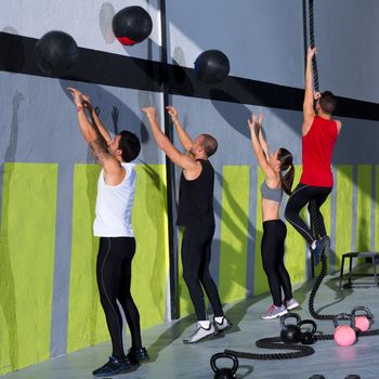Crossfit workout people group with wall balls and rope at fitness gym