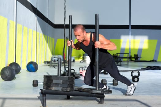 Crossfit sled push man pushing weights workout exercise