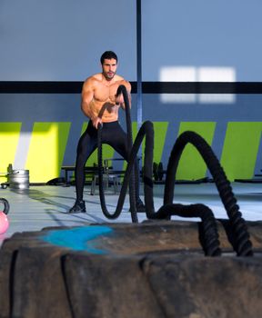 Crossfit battling ropes at gym workout from big tires