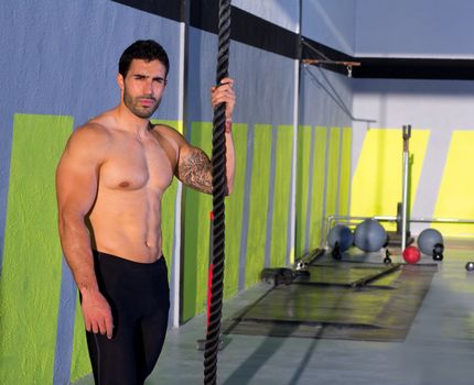 Crossfit handsome man with climbing rope relaxed at gym