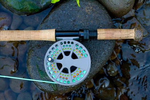 A fly fishing rod and reel sit upon some river rock on the edge of the Willamette River in Oregon.