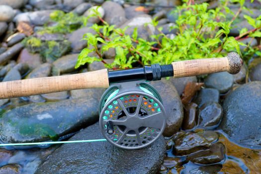 A fly fishing rod and reel sit upon some river rock on the edge of the Willamette River in Oregon.