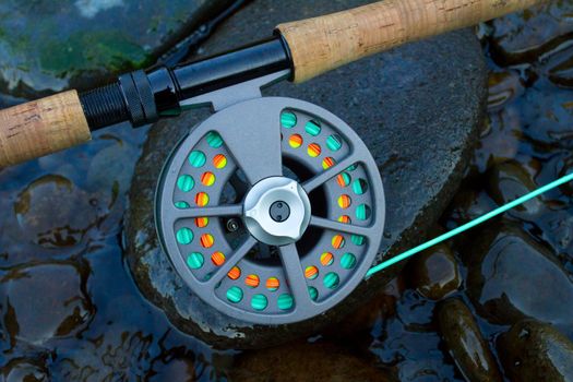 A fly fishing rod and reel sit upon some river rock on the edge of the Willamette River in Oregon.