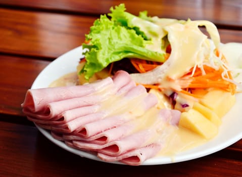 Ham with salad on wooden table