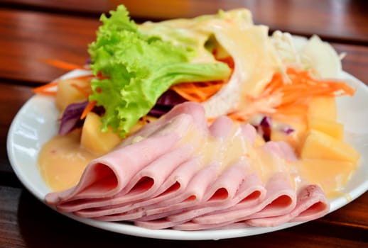 Ham with salad on wooden table