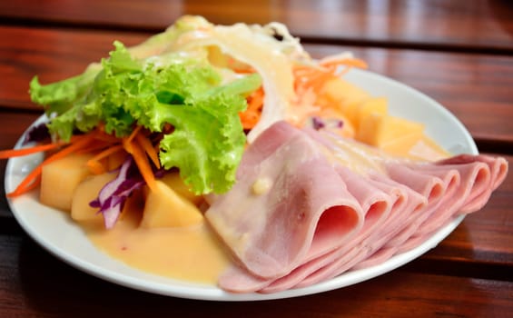 Ham with salad on wooden table