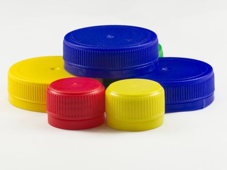 Bunch of multicolored used plastic bottle caps on white background