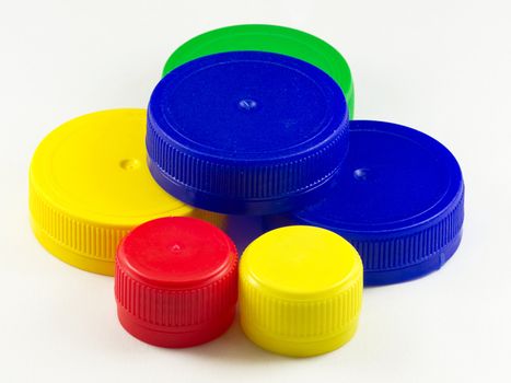 Bunch of multicolored used plastic bottle caps on white background