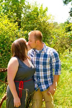 A man and a woman are in an overgrown field with rusted farm equipment.