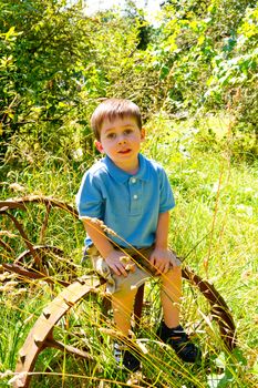A young child is playing in a blue polo shirt near some farm equipment outdoors.
