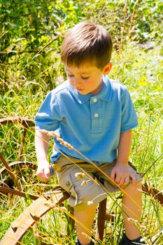 A young child is playing in a blue polo shirt near some farm equipment outdoors.