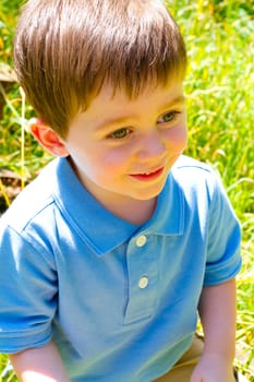 A young boy is playing outdoors while wearing a blue polo shirt.