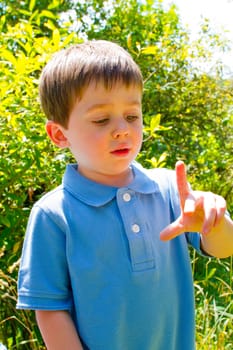 A young boy is playing outdoors while wearing a blue polo shirt.