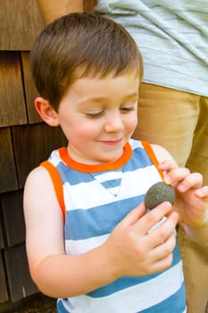 A boy is playing with an object outdoors while standing with his father.